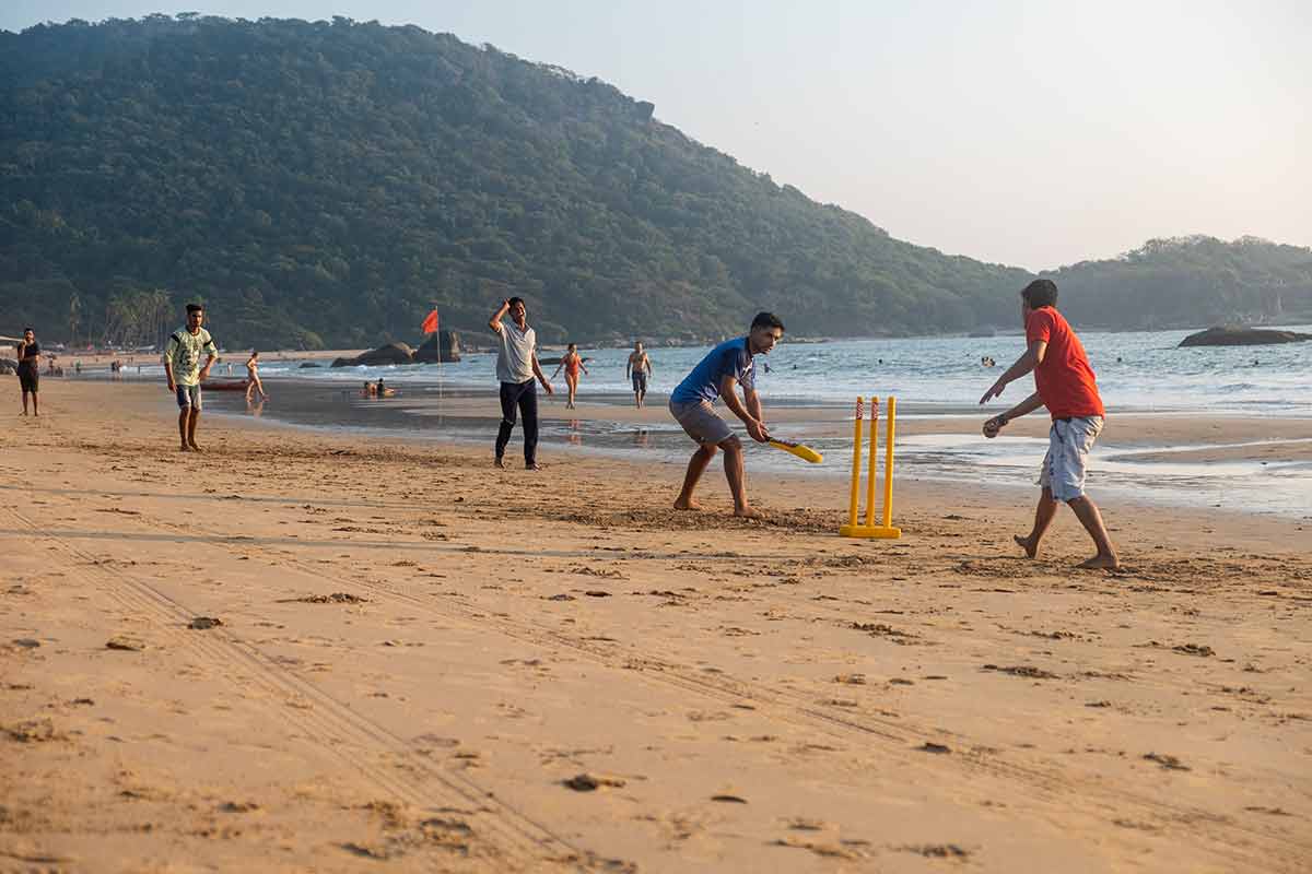 does india have beaches group of Indian adults playing cricket on beach at sunset, Goa, India.