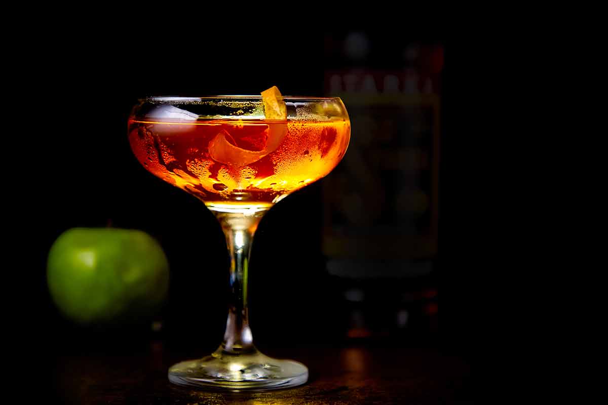 drinks in spanish red cocktail with lemon slice and a green apple with black background