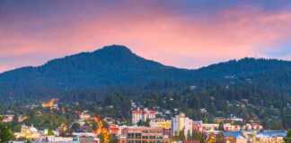 20 Oregon Cities And Towns That Are Perfect For Your Next Adventure distant view of eugene at sunset with mountain backdrop
