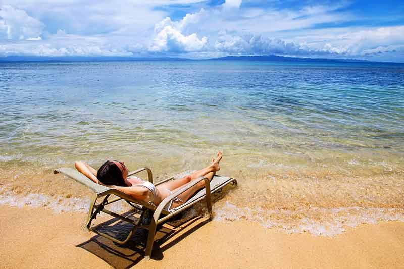 fiji beaches taveuni island woman in a bikini relaxing on a lounge chair on one of the beaches in Fiji