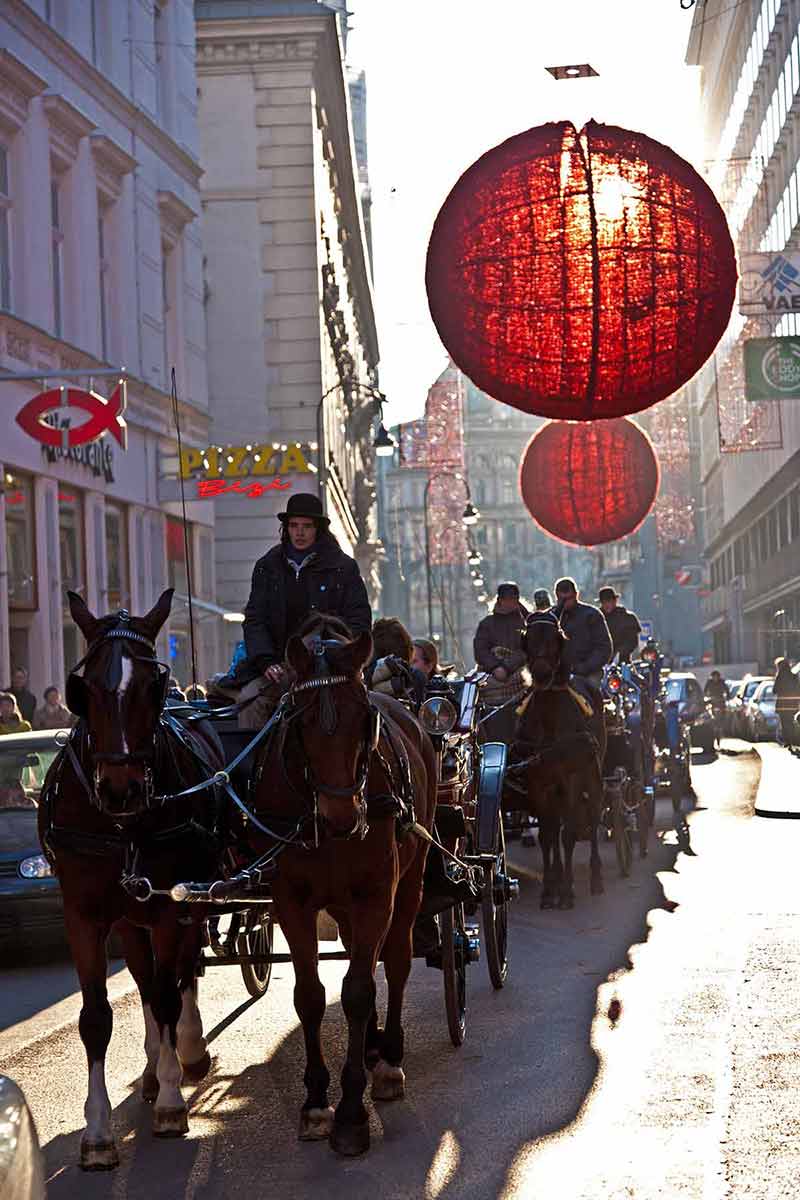 fun Christmas in Vienna horse and buggies under red street baubles