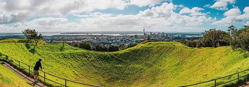 Man leaning on fence admiring the view of Auckland city from Mt Eden Park
