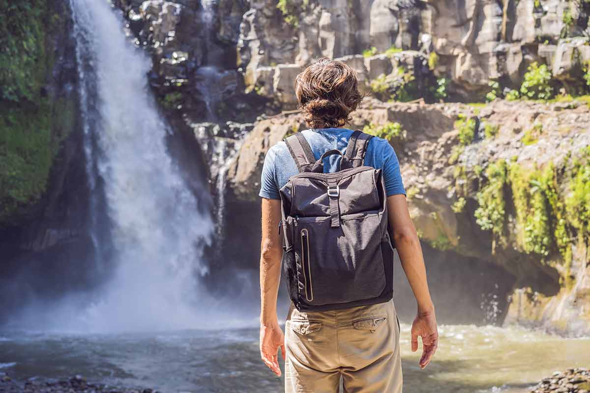 Man with backpack looking at a waterfall