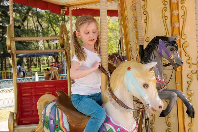 fun things to do in raleigh A child rides colorful carousel with horses in an amusement park