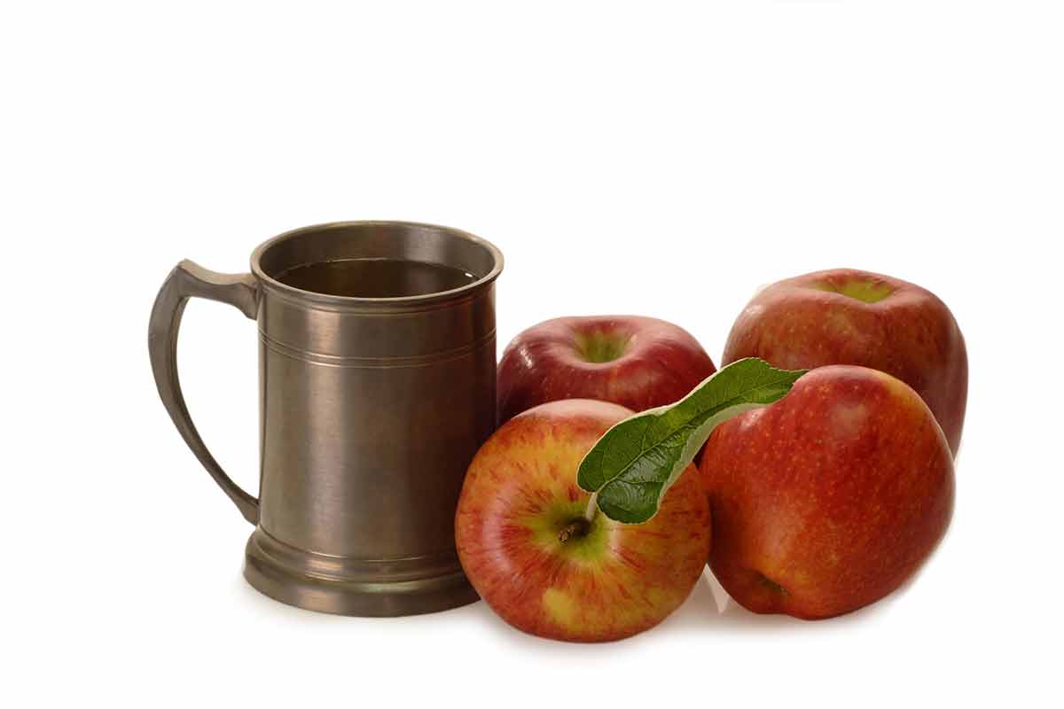 german drinks tankard with four apples on a white background