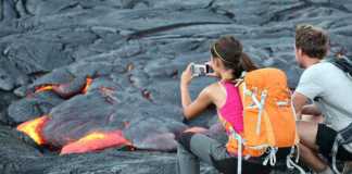 hawaii national parks license plate man and woman taking photo of flowing lava from Kilauea volcano