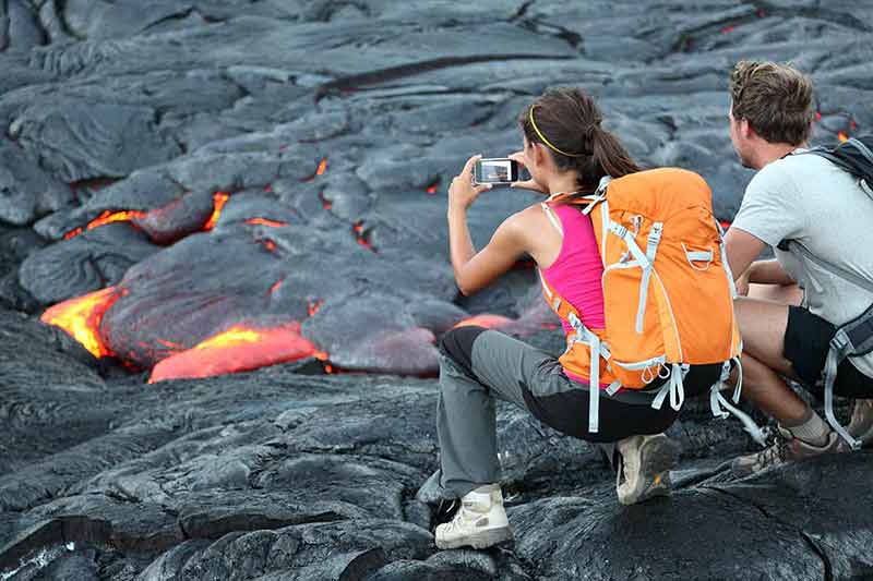 hawaii national parks license plate man and woman taking photo of flowing lava from Kilauea volcano
