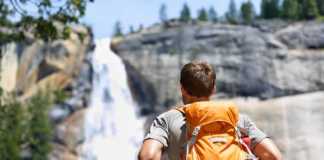 hiking trails with waterfalls in california Hiker hiking with backpack looking at waterfall in Yosemite park in beautiful summer nature landscape