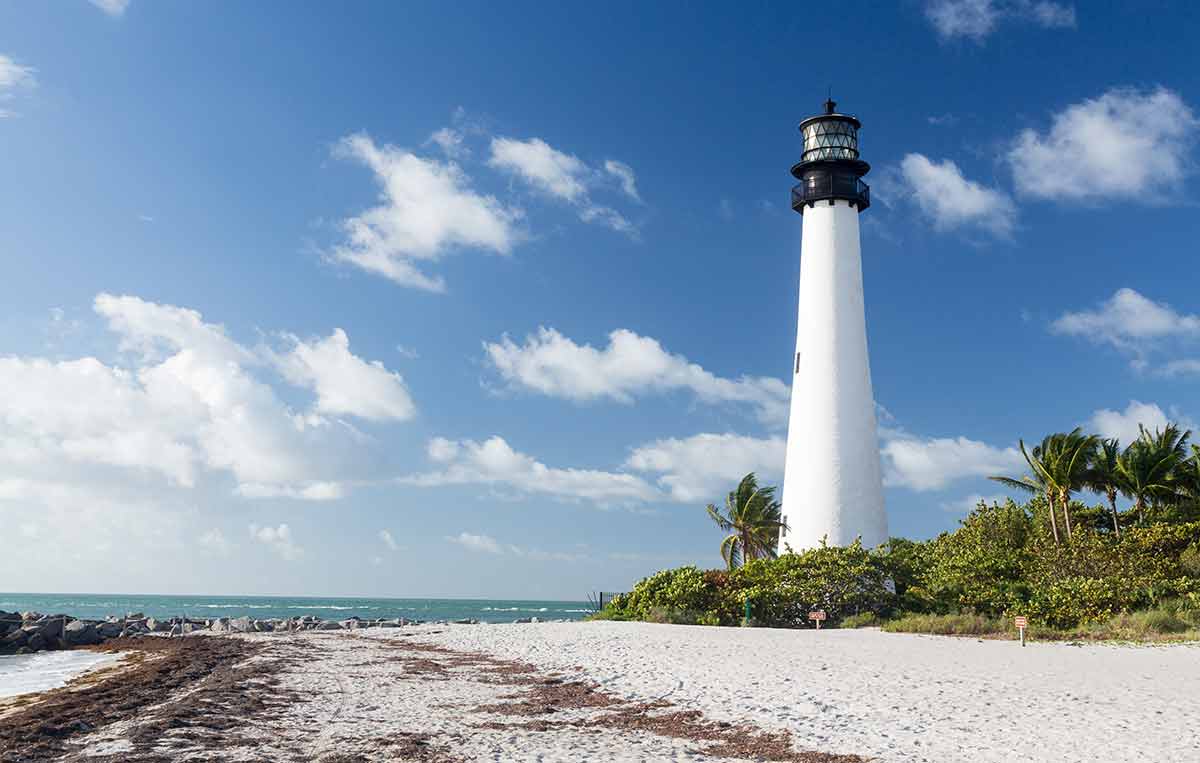 historical landmarks in miami florida white lighthouse against blue sky with whitei sand and palm trees around it