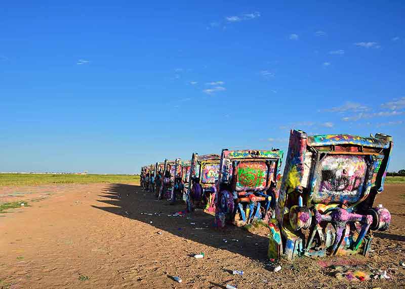 wrecked painted cars buried in the sand as sculptures