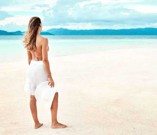 woman in white sarong standing on a beach in indonesia
