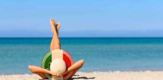 italy beaches model in a large hat with italian colours lying on beach