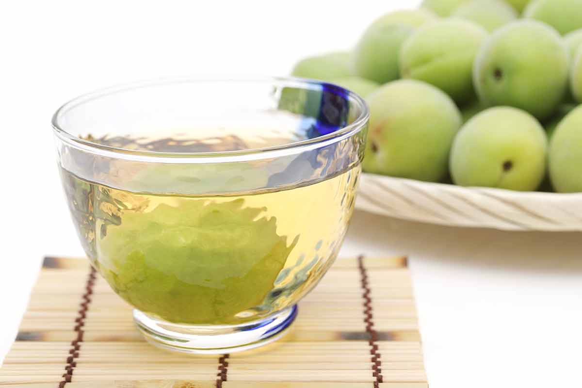 japanese drinks alcohol umeshu in a bowl with green plums in background