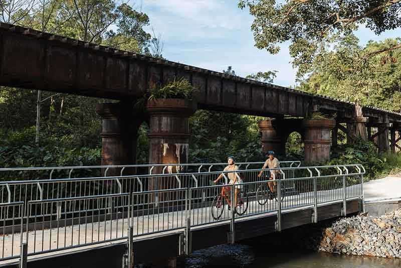 a couple cycling across a bridge on the northern rivers rail trail