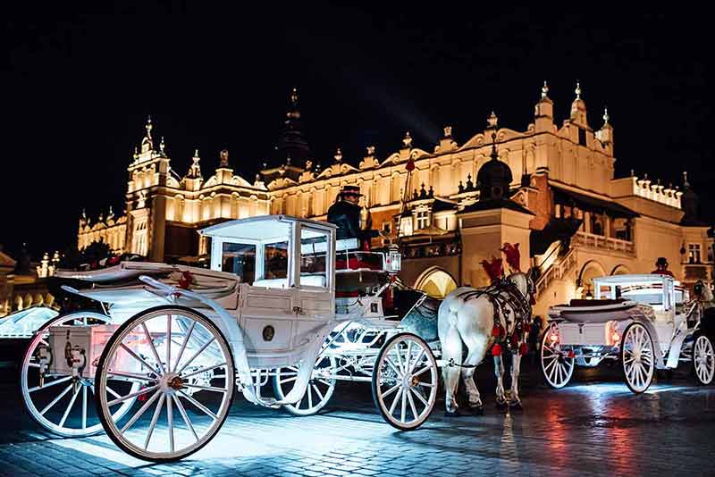 krakow square at night white carriages and horses