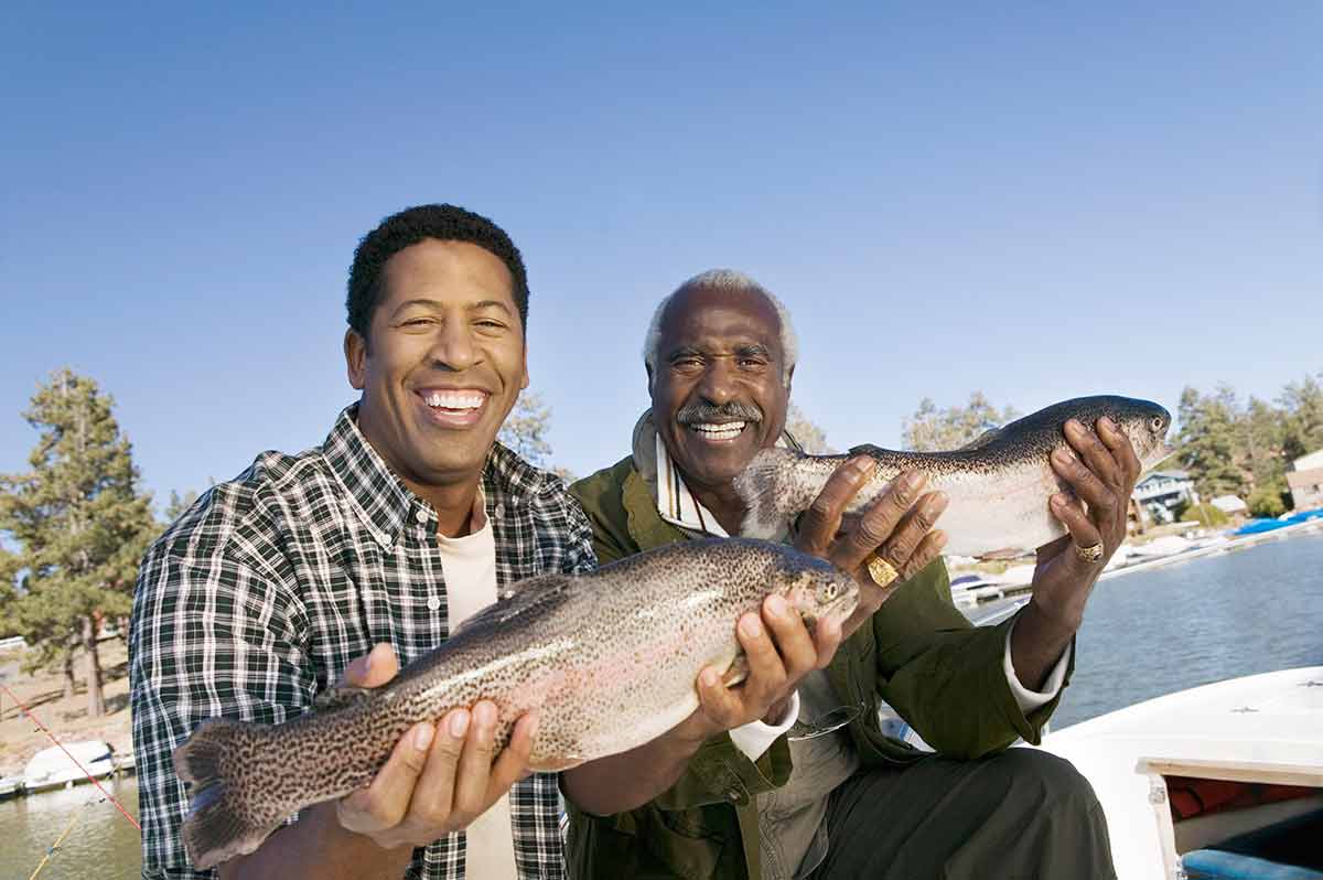 Portrait Of Happy Father And Son Showing Freshly Caught Fish