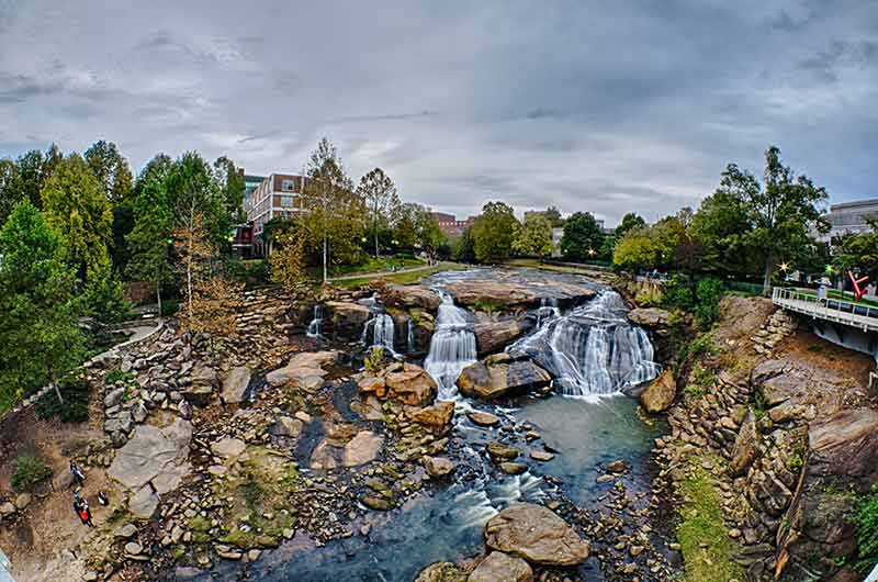 landmarks in south carolina Falls Park with waterfalls, trees and city in the background
