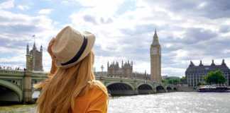 london in summer Back view of traveler girl enjoying sight of Westminster bridge and palace on River Thames with famous Big Ben tower in London, UK.