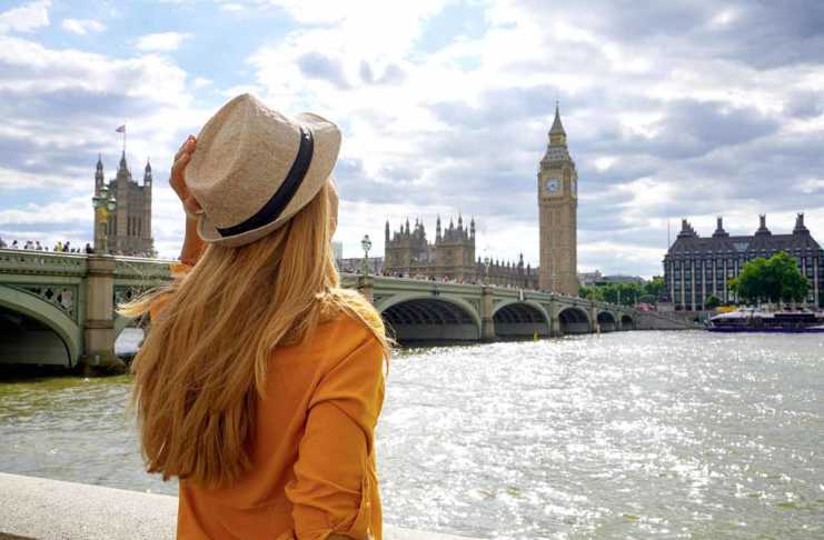 london in summer Back view of traveler girl enjoying sight of Westminster bridge and palace on River Thames with famous Big Ben tower in London, UK.