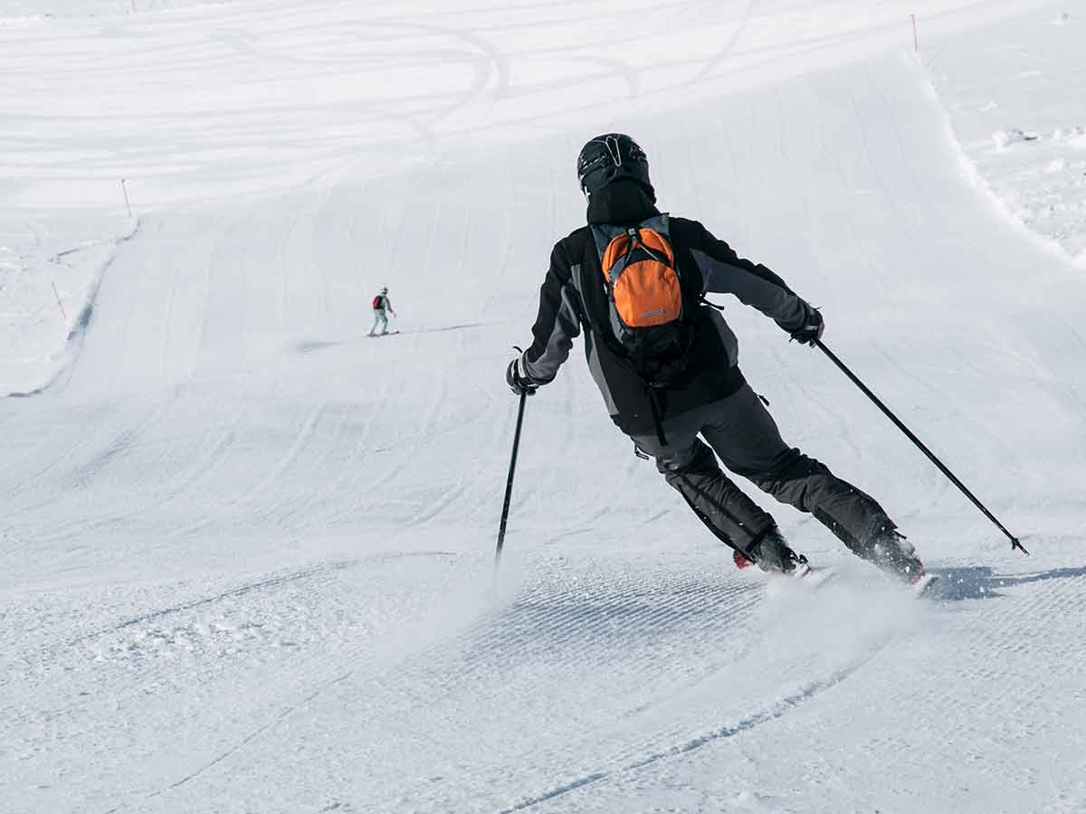 Skier In Black Downhill Skiing On A Ski Slope