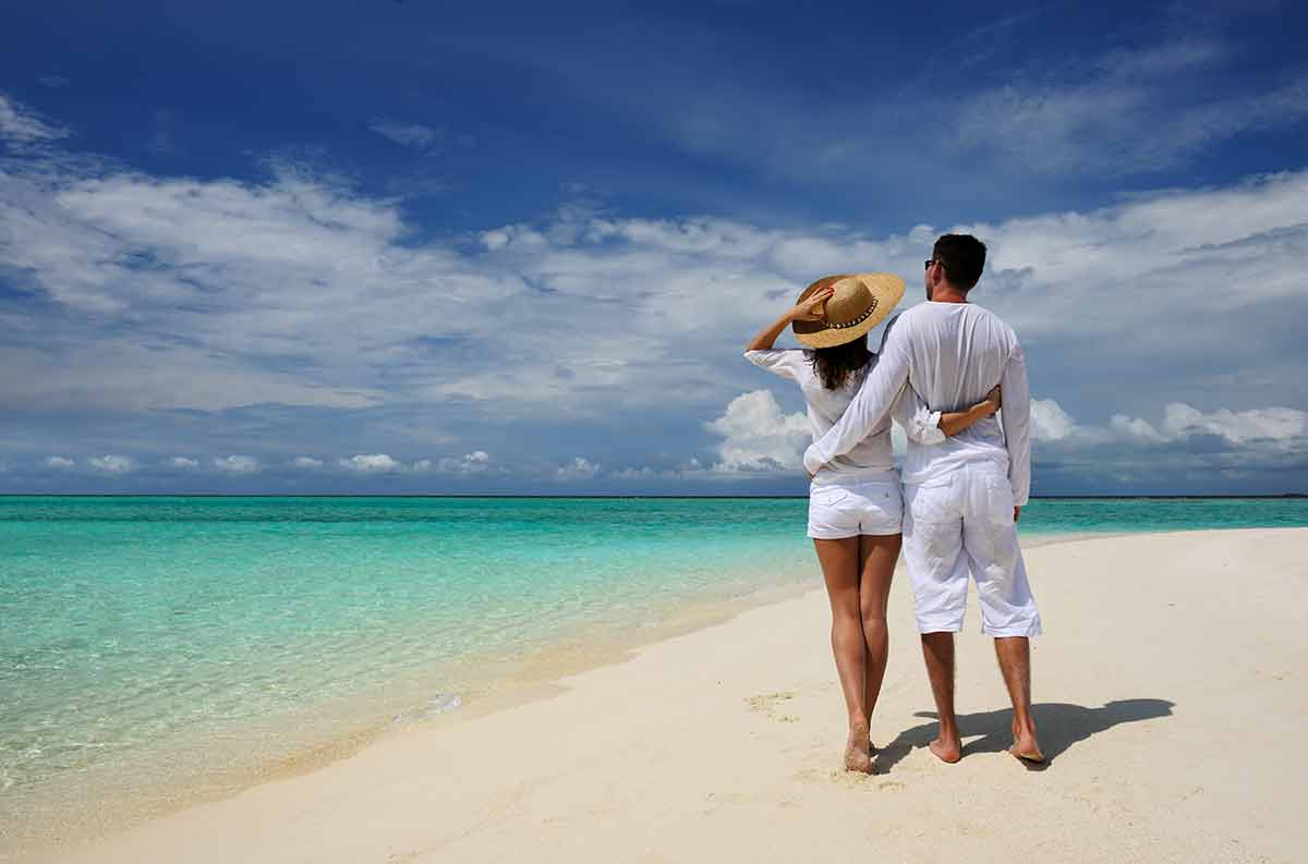 maldives beaches resort couple wearing white clothing on the beach with arms around each other
