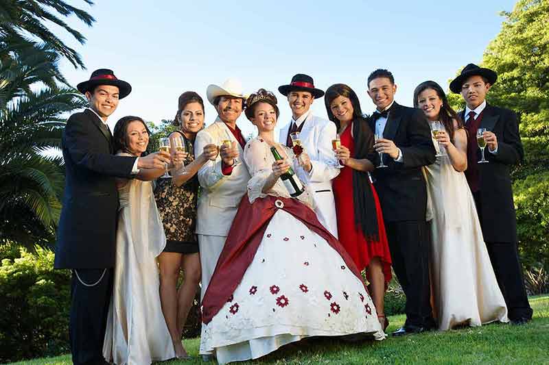 mexican quinceanera traditions - group of young people dressed up in finery holding champagne flasses