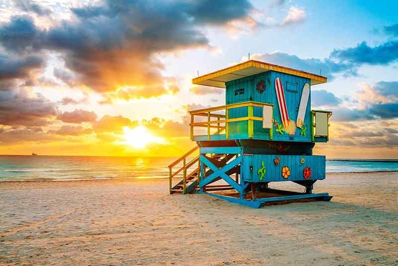 miami beach landmarks sunrise with lifeguard tower and coastline with colorful cloud and blue sky.