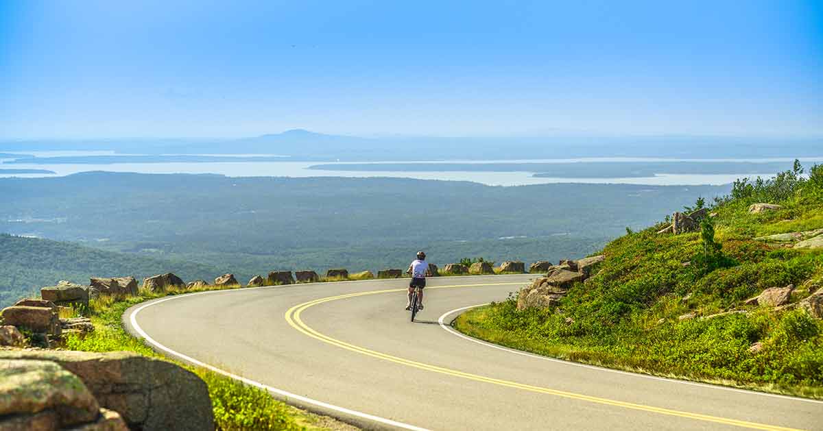 national parks near portland maine Female mountain bike cyclist riding downhill along Cadillac Mountain road