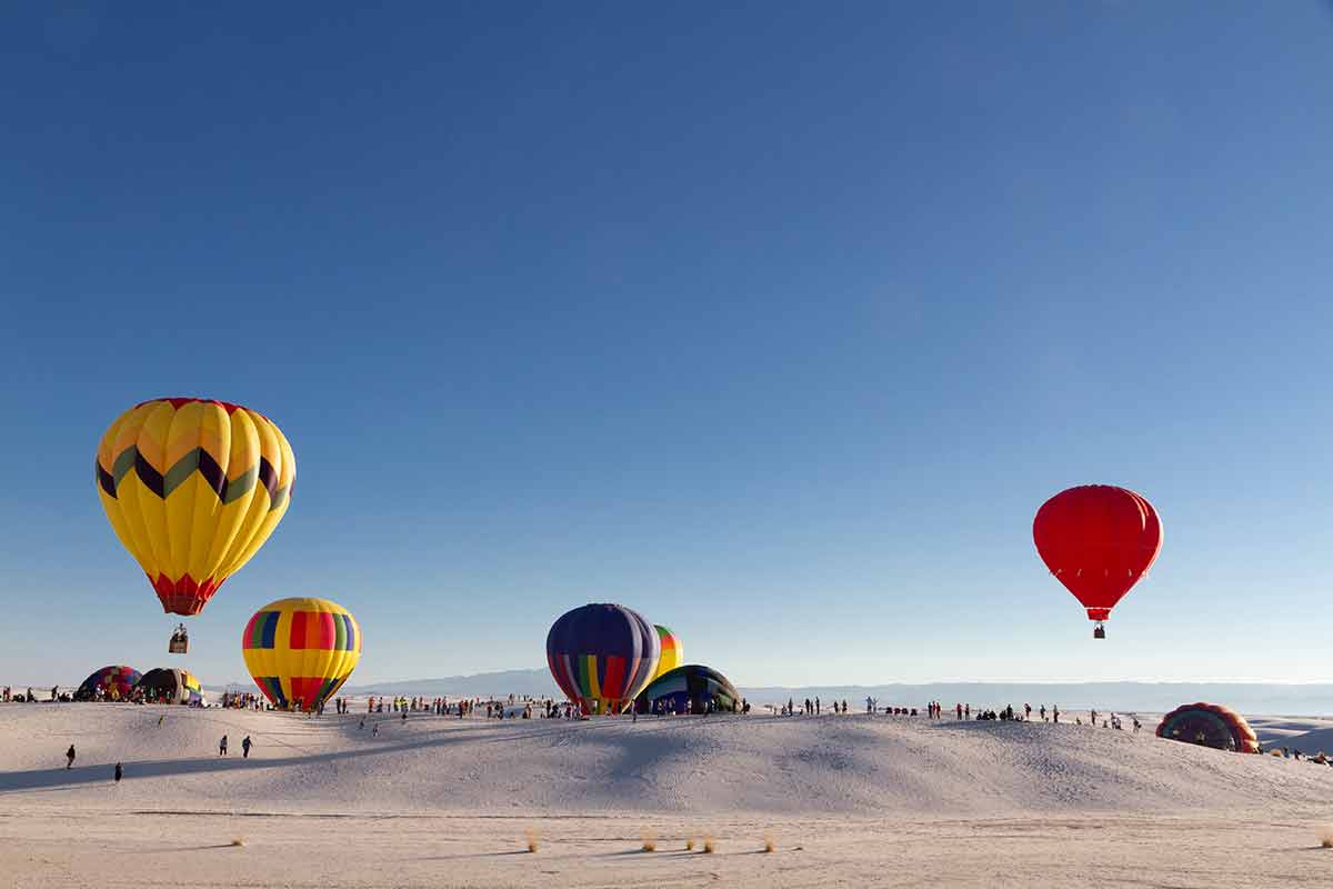 new mexico national parks and monuments yellow, red and blue multicoloured balloons taking off over the desert