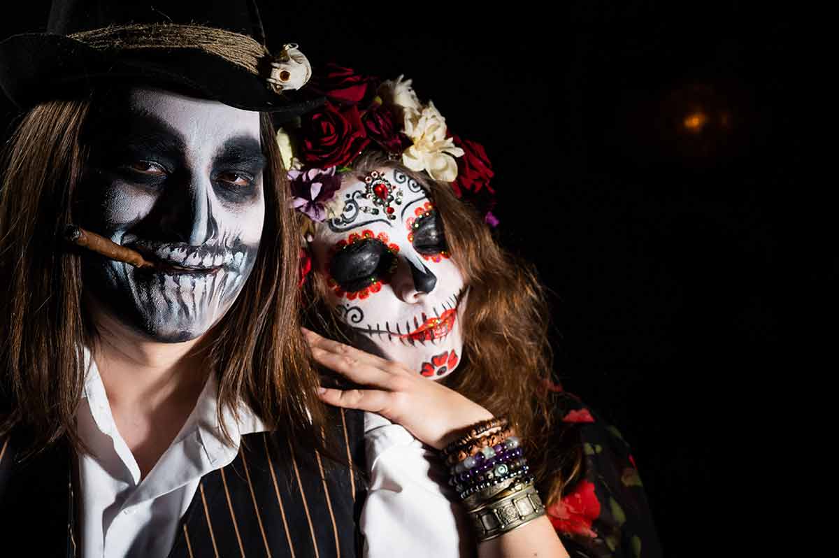 out at night in mexico city Woman in santa muerte costume and man in skeleton bodypainting for halloween