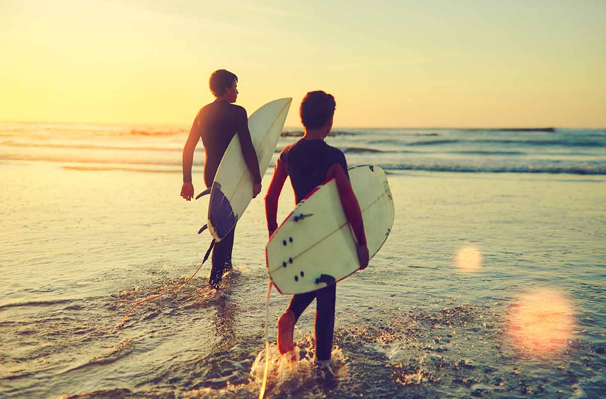 two young brothers carrying their surfboards