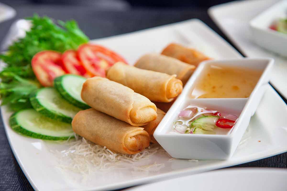 plate of spring rolls, salad and condiments