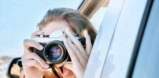woman with camera looking out of a car
