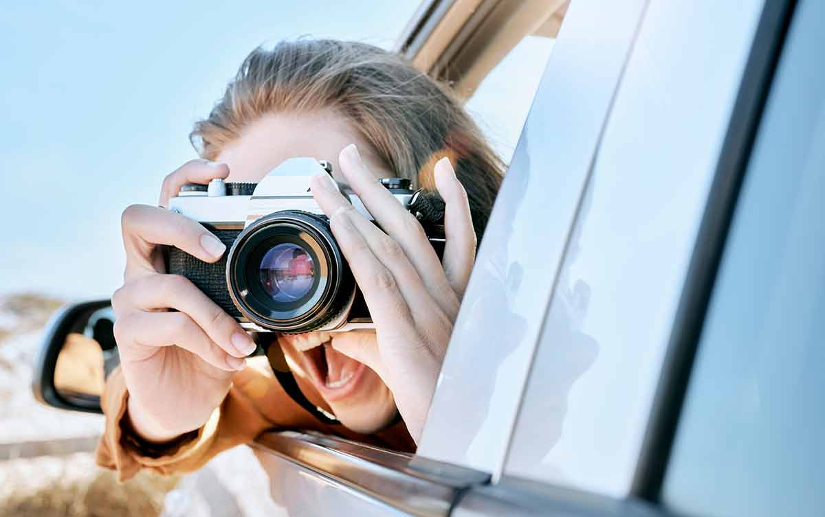woman with camera looking out of a car