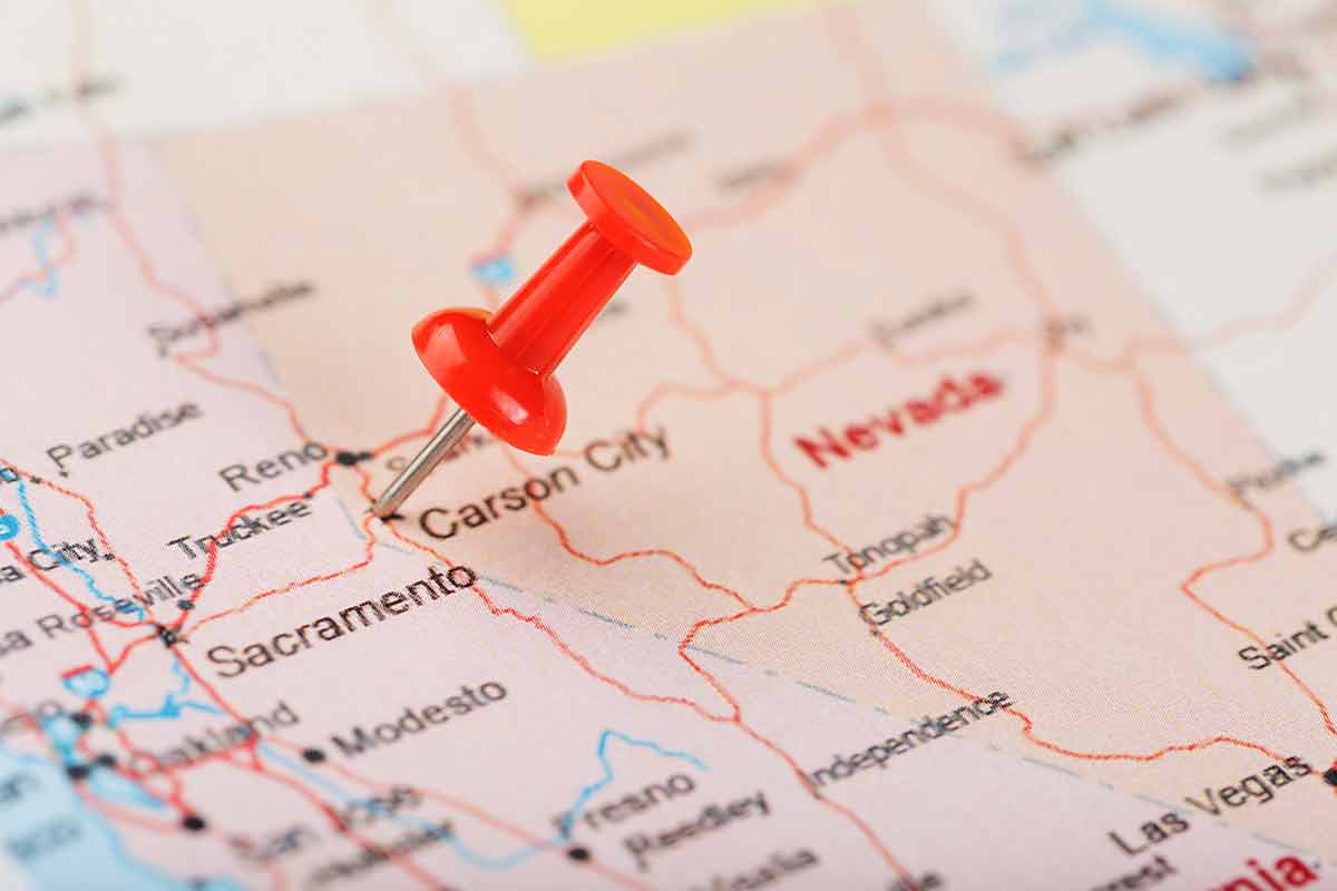 Red clerical needle on a map of USA, Nevada and the capital Carson City.