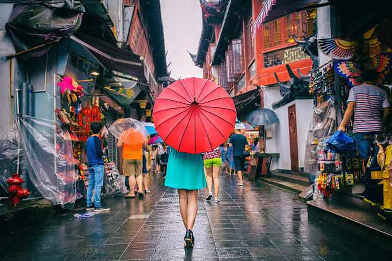 shanghai mall at night woman carrying a red umbrella walking through a shopping street in the rain.
