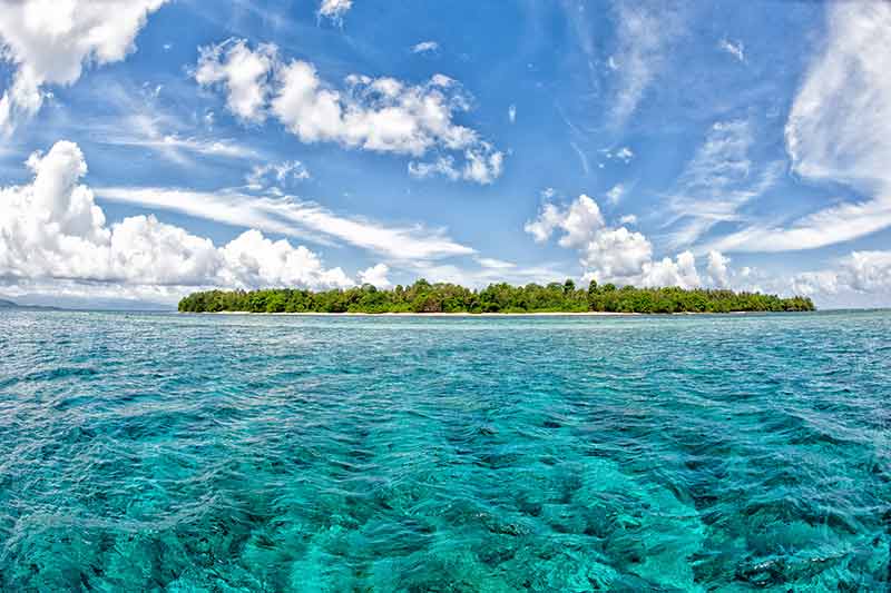siladen island with aquamarine water and blue sky