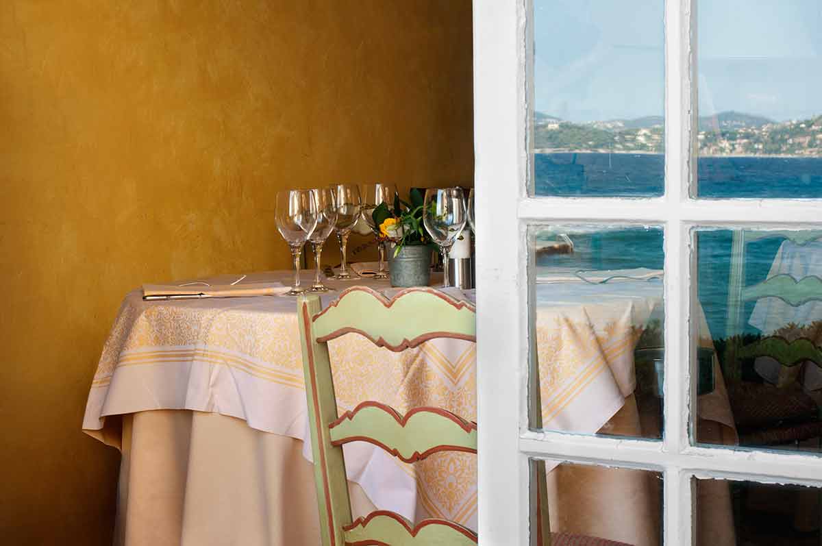 Arranged table in a restaurant and open window. Reflection of the sea on the window