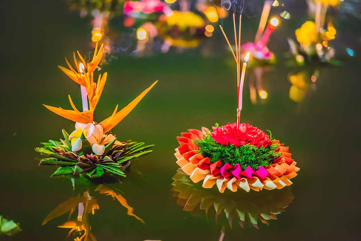 the best time of year to visit thailand buy flowers and candle to light and float on water to celebrate the Loy Krathong festival in Thailand.