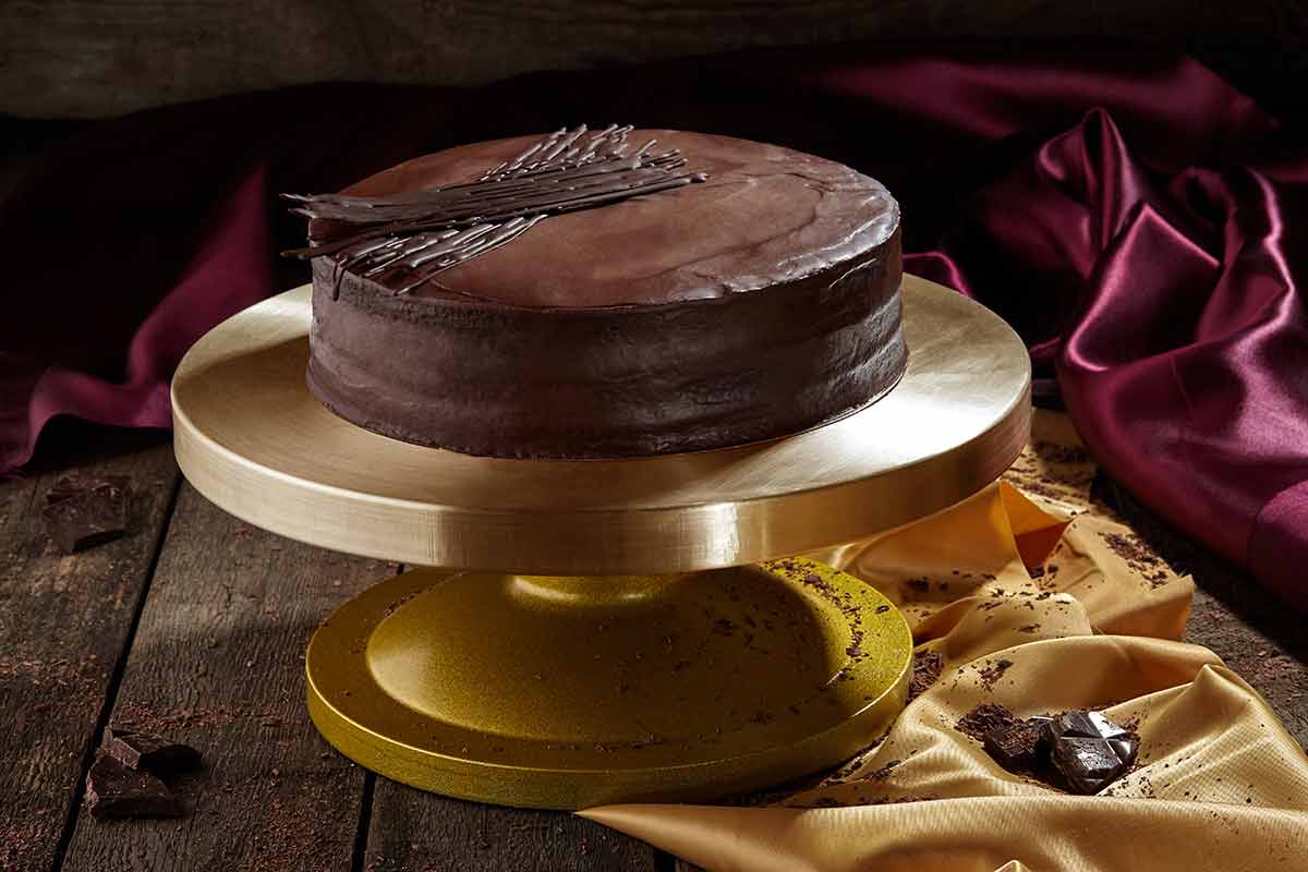 things to do at night in vienna Traditional Austrian layered sponge cake Sachertorte with dark chocolate ganache served on stand on rustic wooden background.