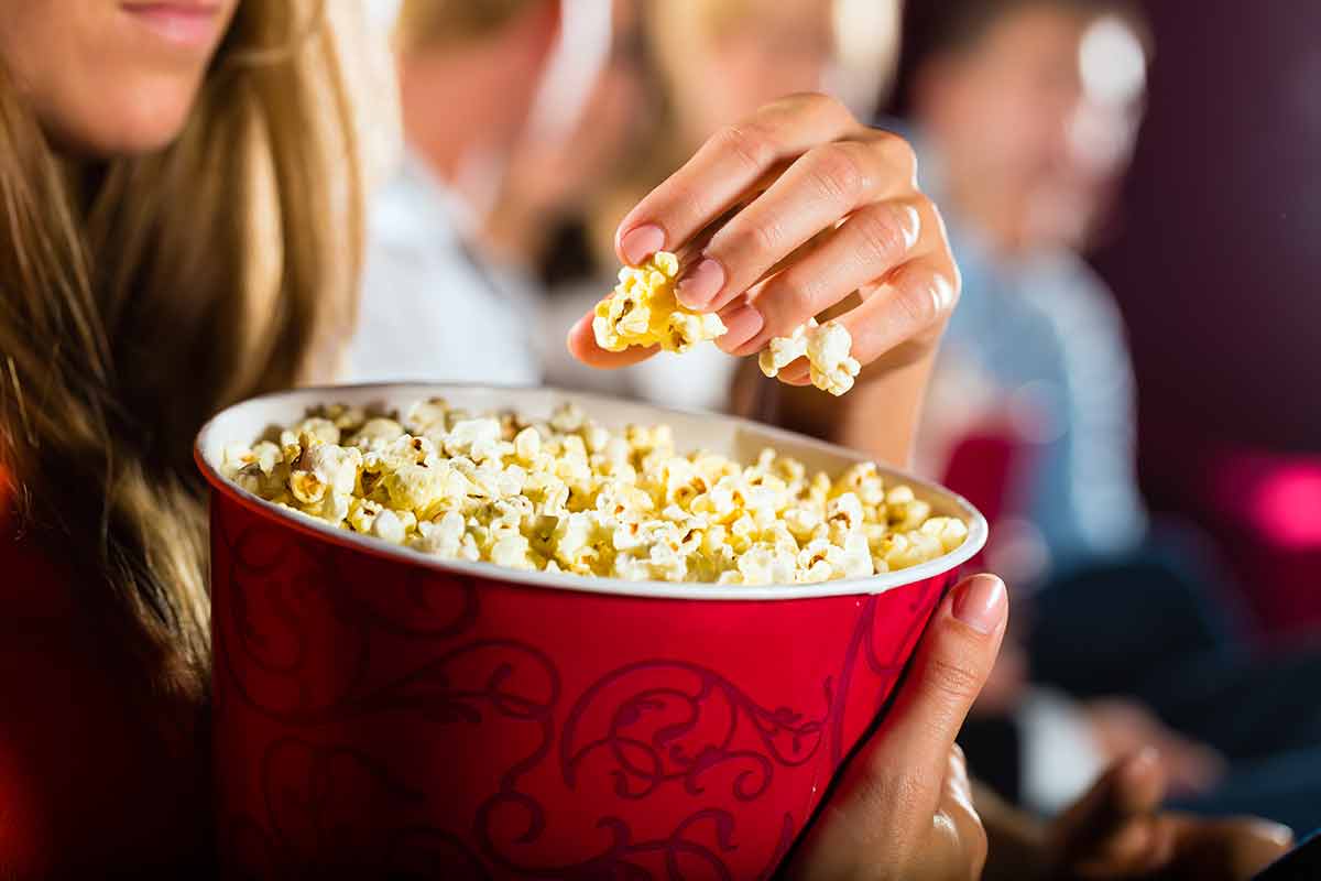 things to do concord nh Woman eating large container of popcorn in cinema or movie theater.