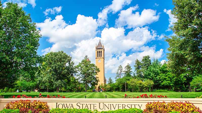 Iowa State University tower, blue sky and green lawns with sign