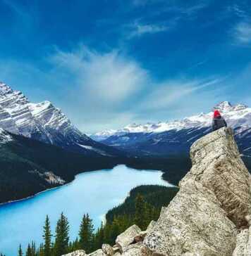 woman sitting on a rock in Peyto Lake, Banff National Park In Canada With The Canadian Rockies