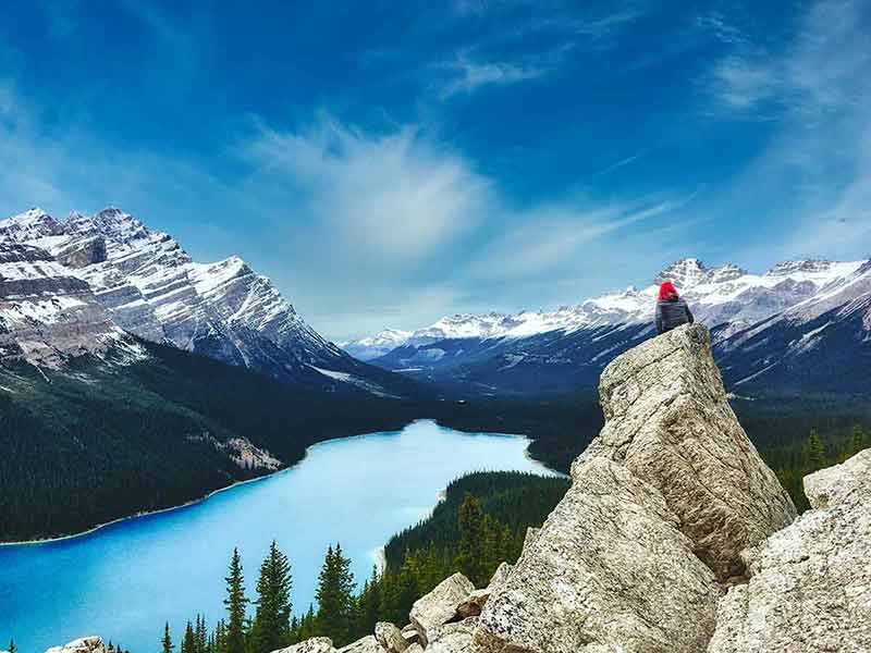 woman sitting on a rock in Peyto Lake, Banff National Park In Canada With The Canadian Rockies