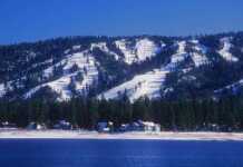 20 Things To Do In Big Bear For The Perfect Mountain Escape Snow-covered ski slopes form the backdrop for Big Bear, California with Big Bear Lake in the foreground.