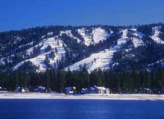 20 Things To Do In Big Bear For The Perfect Mountain Escape Snow-covered ski slopes form the backdrop for Big Bear, California with Big Bear Lake in the foreground.