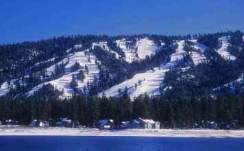 20 Things To Do In Big Bear For The Perfect Mountain Escape Snow-covered ski slopes form the backdrop for Big Bear, California with Big Bear Lake in the foreground.