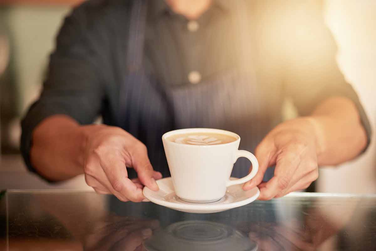 Coffee, cafe and hands of waiter with cup on table in restaurant