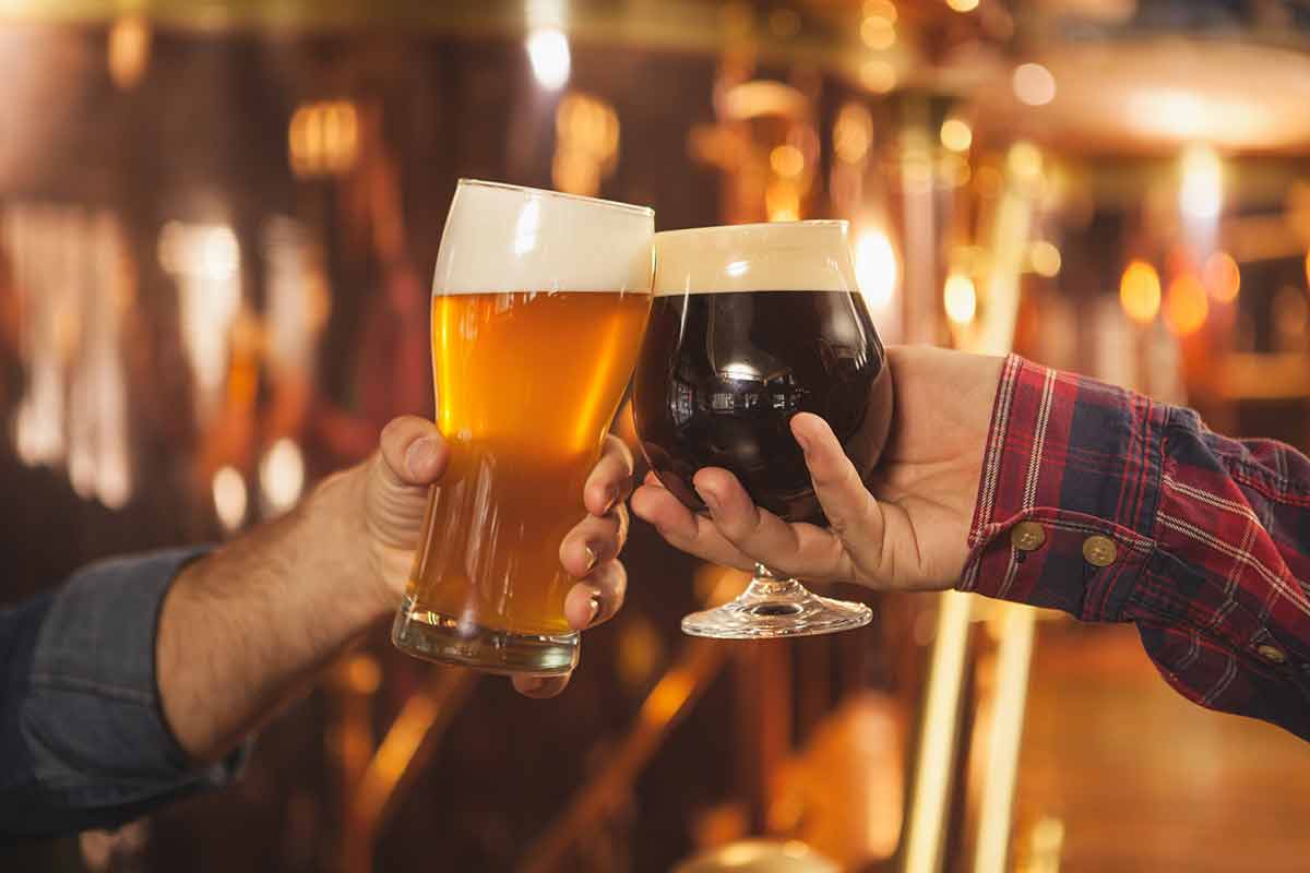 Cropped close up of two men clinking beer glasses together