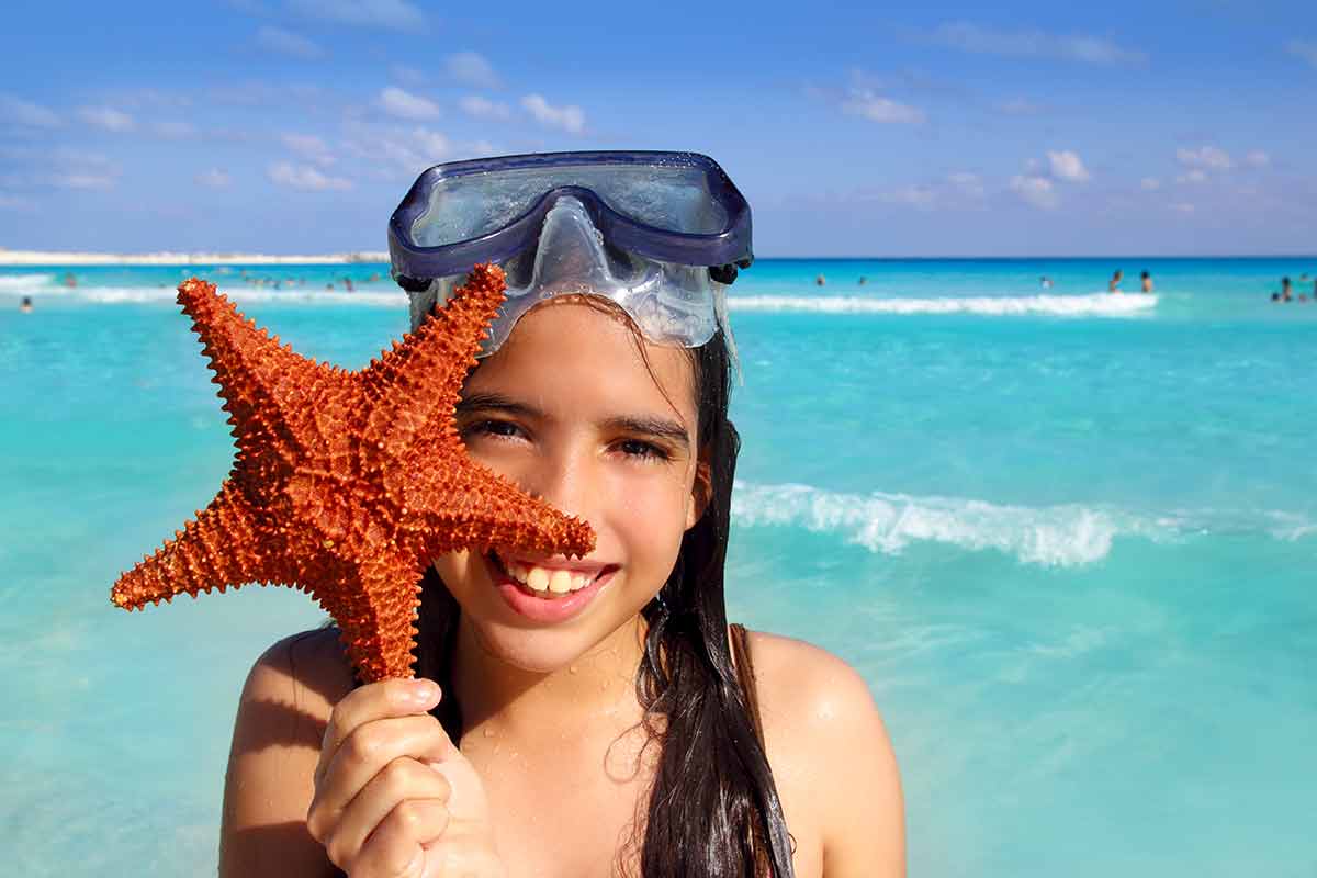 things to do in cancun with kids latin snorkelling girl holding starfish in tropical beach